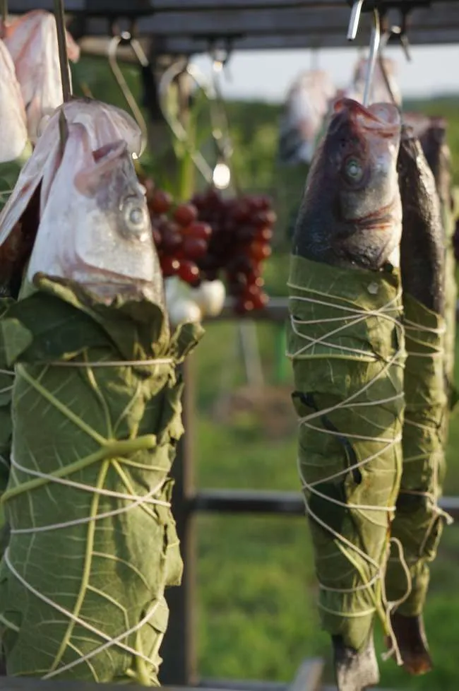 Close detail of hands tying a banana leaf around fish